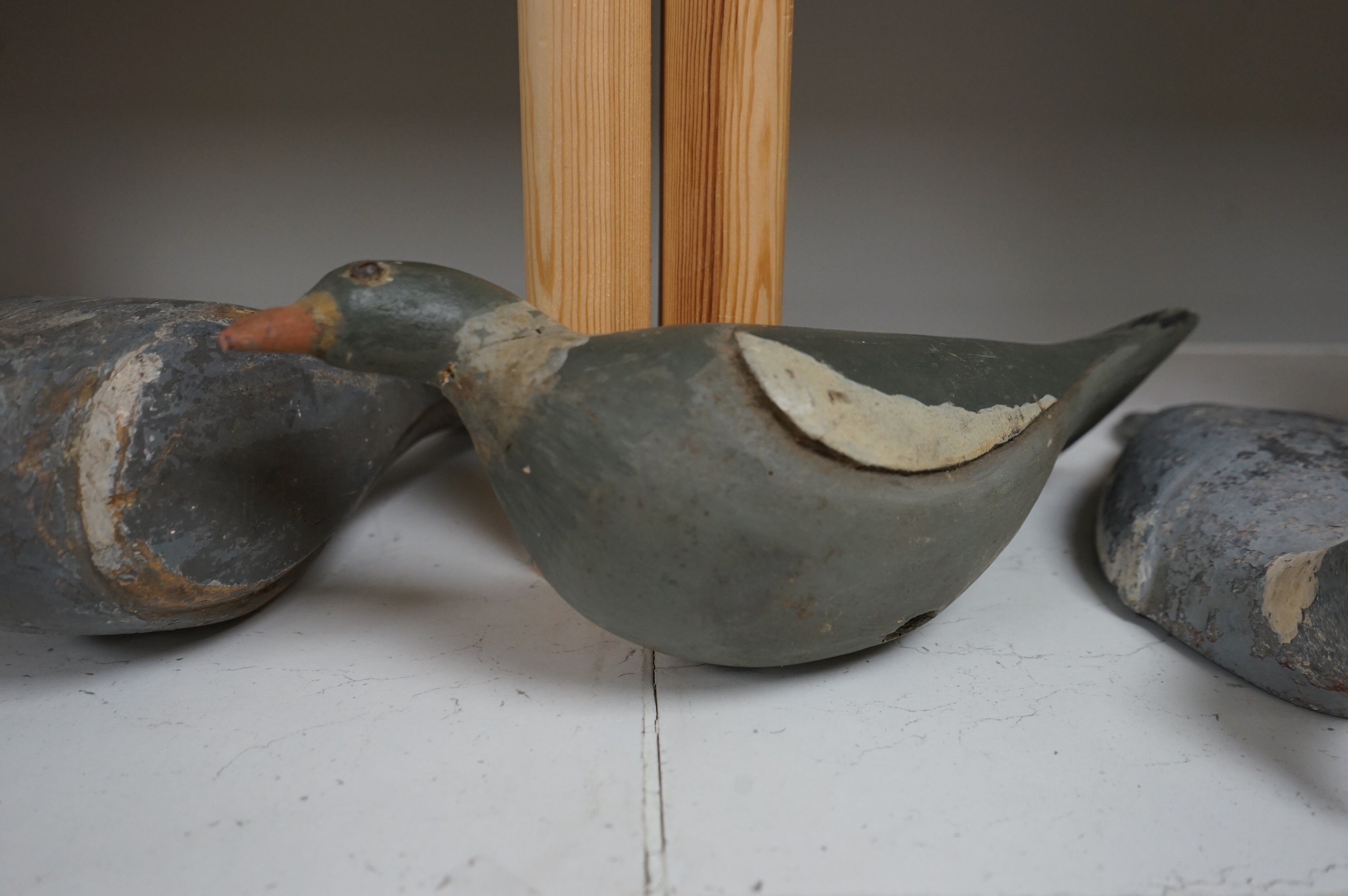 Three early 20th century carved wood decoy pigeons and a later cast metal decoy. Largest 35cm long. Condition - variable